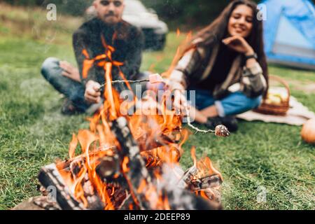 Beautiful couple roasting marshmallows over the campfire Stock Photo