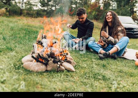 Beautiful couple roasting marshmallows over the campfire Stock Photo