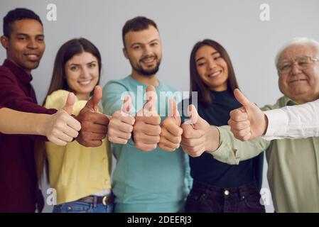 Group of happy people giving thumbs-up, approving of an idea or showing customer satisfaction Stock Photo