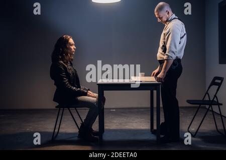 The chief of the police Department charges a detained white man with tattoos on his face in an interrogation room. A man in handcuffs. Stock Photo