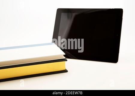 Modern education combines essential digital and paper resources to maximize individual learning styles. Stock Photo