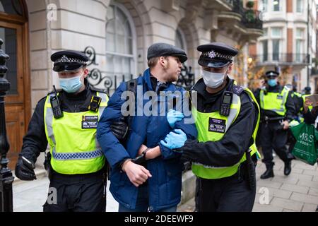 Anti-lockdown protest, London, 28 November 2020. An arrested protester looks back as he is led away by police officers. Stock Photo