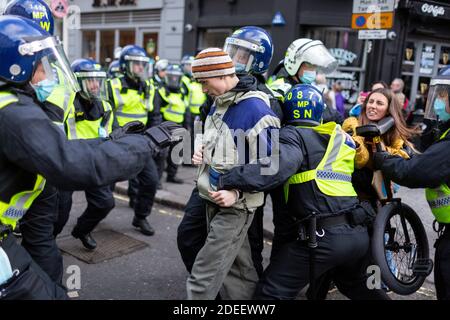 Anti-lockdown protest, Regent Street, London, 28 November 2020. An arrested protester is led away by police officers. Stock Photo