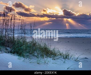 Rays filter through the clouds as the sun begins to rise on the Outer Banks Stock Photo