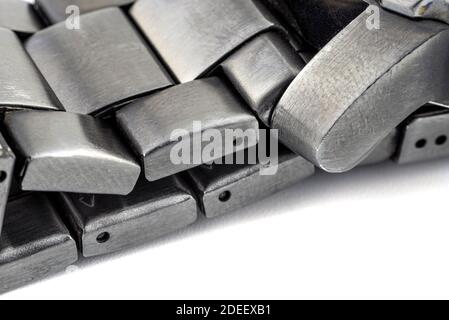 A macro shot of a dark metal stainless steel watchband, isolated on a white background. Stock Photo