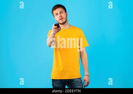 Guy holding remote control isolated on blue background Stock Photo