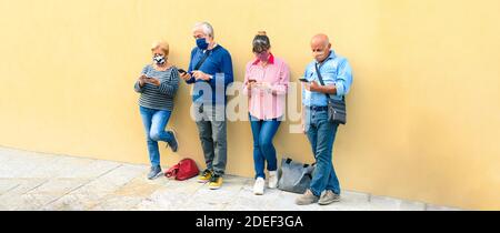 Senior people using mobile smart phone with face mask covered - Retired adults worried while watching news on smartphone - New normal lifestyle concep Stock Photo