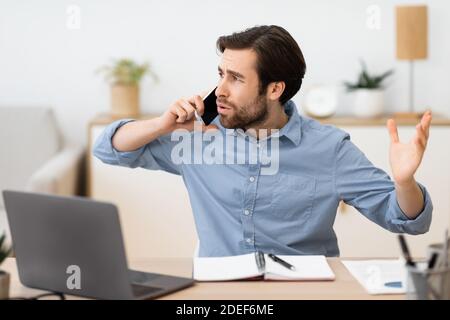 Angry Businessman Calling By Phone Having Problems Sitting At Workplace Stock Photo