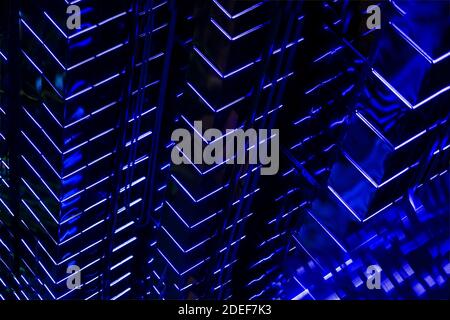 Abstract dark high-rise building at night, modern glass wall with bright blue led backlight Stock Photo