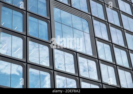 Sky and clouds reflected in windows of pink modern office building ...