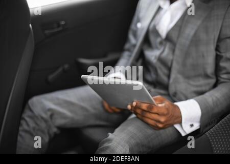 Cropped of african businessman going by car, using pad Stock Photo