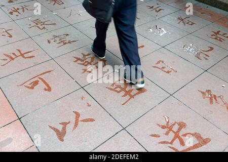 A person walks over water calligraphy on the pavement in Guiyang, China Stock Photo