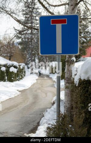 Sign on the road that is indicating that it is a dead end, the street is covered with snow and cleared so that cars can pass. Stock Photo