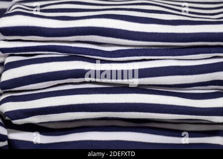 Clothes folded in a pile - ironed striped T-shirts. Stack of vests - sailor's shirts with blue and white stripes close-up Stock Photo