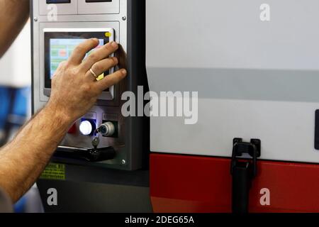 Worker controls the operation of modern equipment using a touch screen. Selective focus. Stock Photo