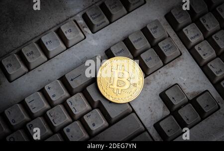 Bitcoin token on top of old dirty computer keyboard background Stock Photo