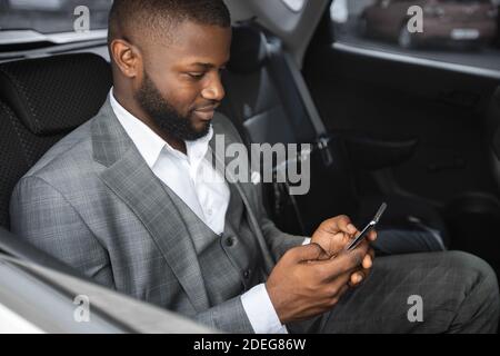 Closeup of african american entrepreneur using mobile phone in car Stock Photo