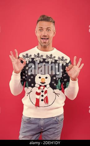 Fashion design for keeping festive. Happy man give OK sign in snowman jumper. Cold weather male style and fashion. Fashion trends for holiday celebration. Take fashion outfit to party level. Stock Photo