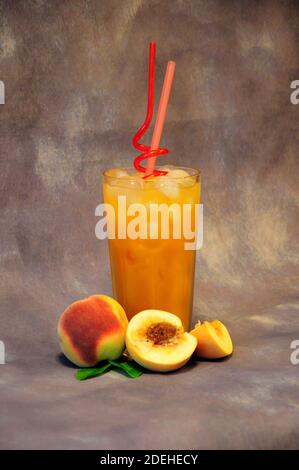 Peach juice with ice and fruits on a gray abstract background. Close-up. Stock Photo