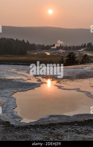 Heart Spring with the Castle Geyser in the distance near sunset in the Upper Geyser Basin of Yellowstone National Park, Wyoming, USA. Stock Photo