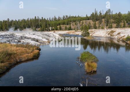 Geyserite mineral deposits from hot springs and geysers line the banks of the Firehole River in Yellowstone National Park, Wyoming, USA. Stock Photo