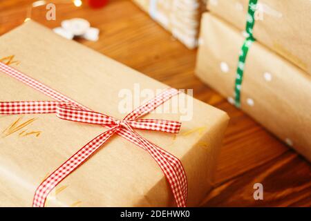 Christmas boxes in wrapping kraft paper on wooden table. Gift boxes with colored ribbons. New year mood. Winter holiday. Stock Photo