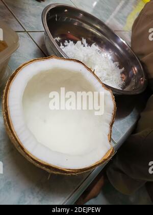 Half of the fresh coconut, with a picture of grated coconut in the background. The key ingredients of Thai desserts Stock Photo