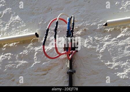 Multi-Colored Cables on an Exterior Wall illuminated by the Morning Sun Stock Photo