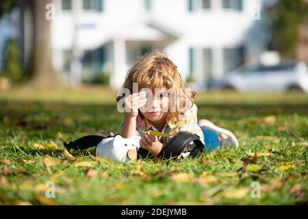 Outdoor portrait of a cute little boy holding money. Child saving with one coin. Portrait kid with piggy bank and coin. Getting started saving money,