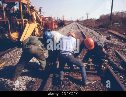 Southern Railway right-of-way work crew jack up a rail they are removing old ties and replacing them with new ones while improving the roadbed. ca. 1974 Stock Photo