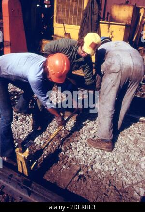 Southern Railway right-of-way work crew jack up a rail they are removing old ties and replacing them with new ones while improving the roadbed.  ca. 1974 Stock Photo