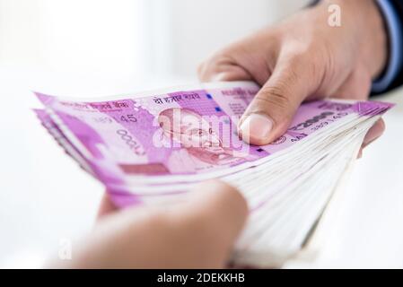 Hands of businessman holding money, Indian Rupee currency, paying cash for the business investment to his partner Stock Photo