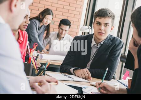Young multiethnic business team meeting at the office desk seriously discussing project Stock Photo