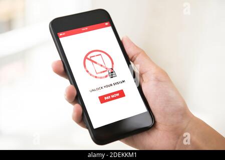 Hand holding smartphone that the system being locked by ransomware, showing on screen - cyber attack concept Stock Photo