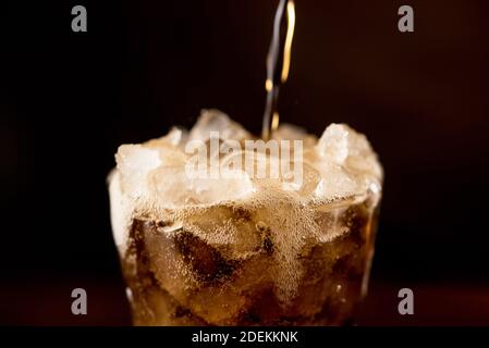 Close up of sparkling carbonated cold fresh cola drink being poured into the glass with overflowed frothy bubble on top Stock Photo