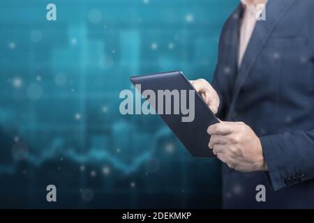 businessman holds a digital tablet on background of financial charts. Business analysis, planing and strategy concept. copy space Stock Photo
