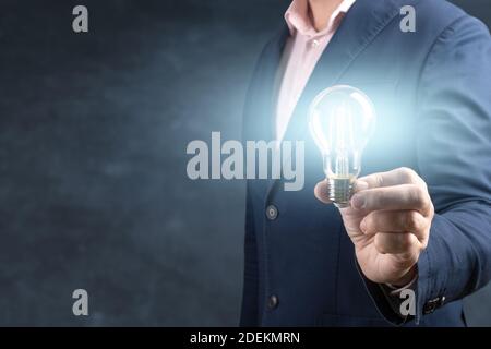 Hand of businessman holding illuminated light bulb on blue background. idea, innovation and inspiration concept. The concept of the business idea Stock Photo