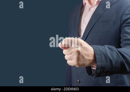 businessman shows fig gesture. Businessman in a blue suit shows a fig sign on blue background. gesture of contempt or rejection of unacceptable condit Stock Photo