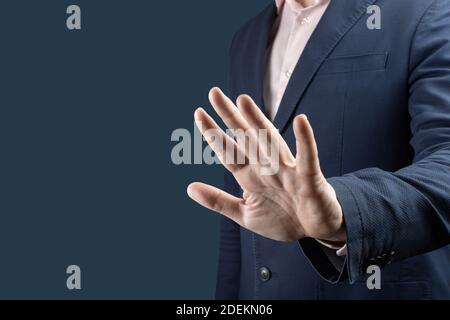 businessman with stop gesture. Businessman in suit making stop gesture, holding his palm outward over blue background. man hand stop sign Stock Photo