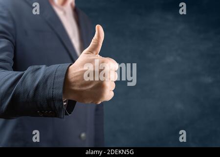 Businessman showing thumbs up - closeup shot. Business man showing thumb up. Person giving the thumbs up over blue background. Business thumbs up conc Stock Photo