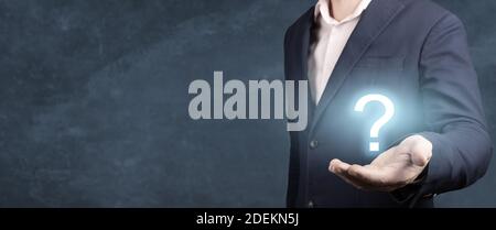 Businessman holding hand question marks in his hand. Businessman showing Question mark. man holds a glowing question mark in his hand. banner, blue ba Stock Photo