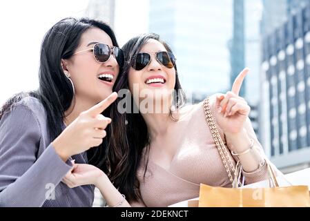 Beautiful young Asian woman friends enjoying traveling and shopping in the city during summer holiday sales season Stock Photo