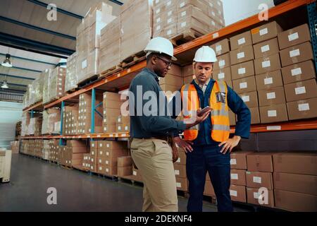 Portrait of a male worker and manger together checking the stock using digital tablet at large storehouse Stock Photo