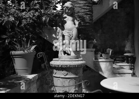 Concrete cupid statue in the backyard of Mediterranean mansion (B/W) Stock Photo