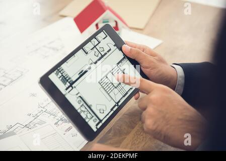 Real estate agent or architect presenting house floor plan to client on tablet computer screen Stock Photo