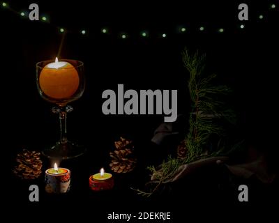 Christmas composition with burning candles, conifer branches, pine cones and fairy lights on a dark background Stock Photo