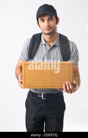 Young man wearing a bag pack standing with a box in his hand to be delivered Stock Photo