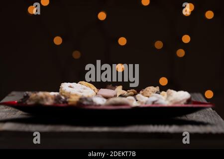 A closeup shot of assorted Christmas cookies on a red tree-shaped plate with a bokeh background Stock Photo