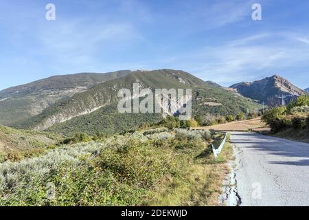 landscape with mountain road and  green slopes of Genzana range in background, shot in bright light near Casale, L'Aquila, Abruzzo, Italy Stock Photo