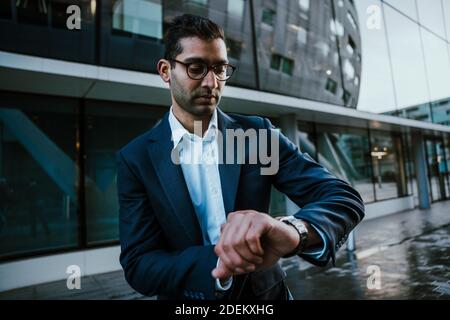 mixed race businessman walking to conference meeting checking time on smart watch Stock Photo